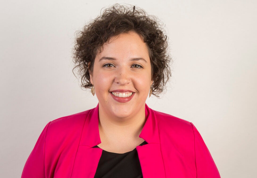 woman with curly hair and pink blazer smiling