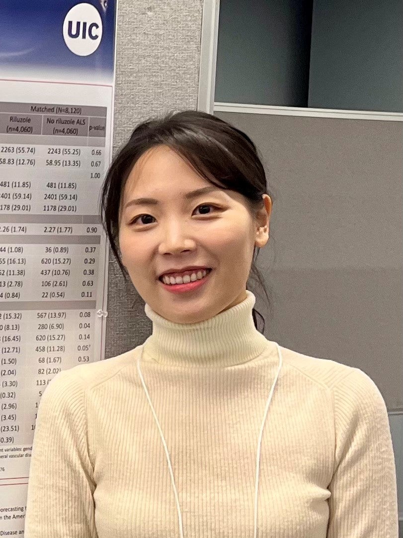 woman in turtleneck standing next to academic poster