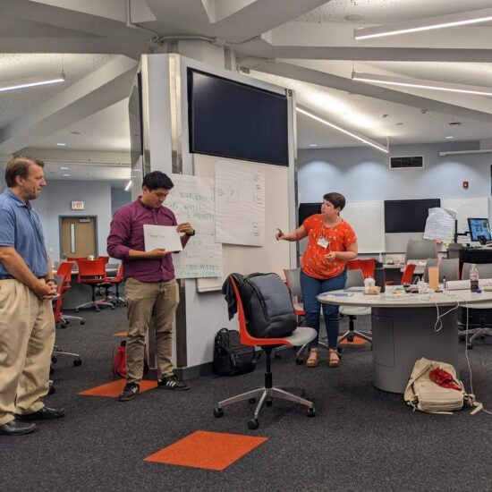 Three people standing around a paper poster.