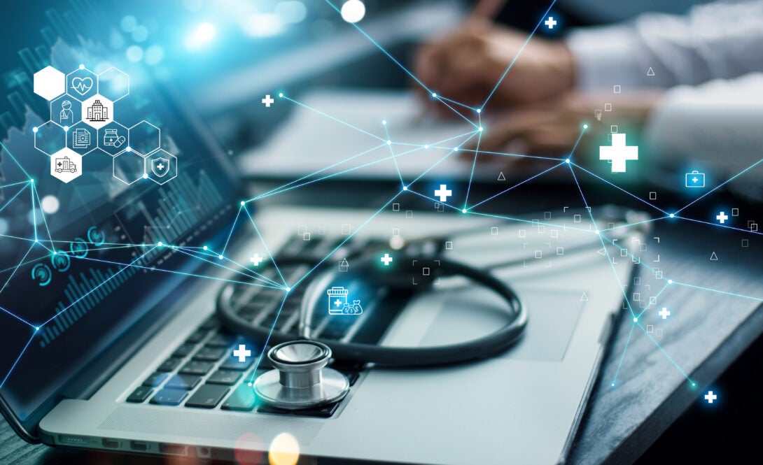 A stethoscope laying on top of a laptop; blue network diagram of various healthcare icons